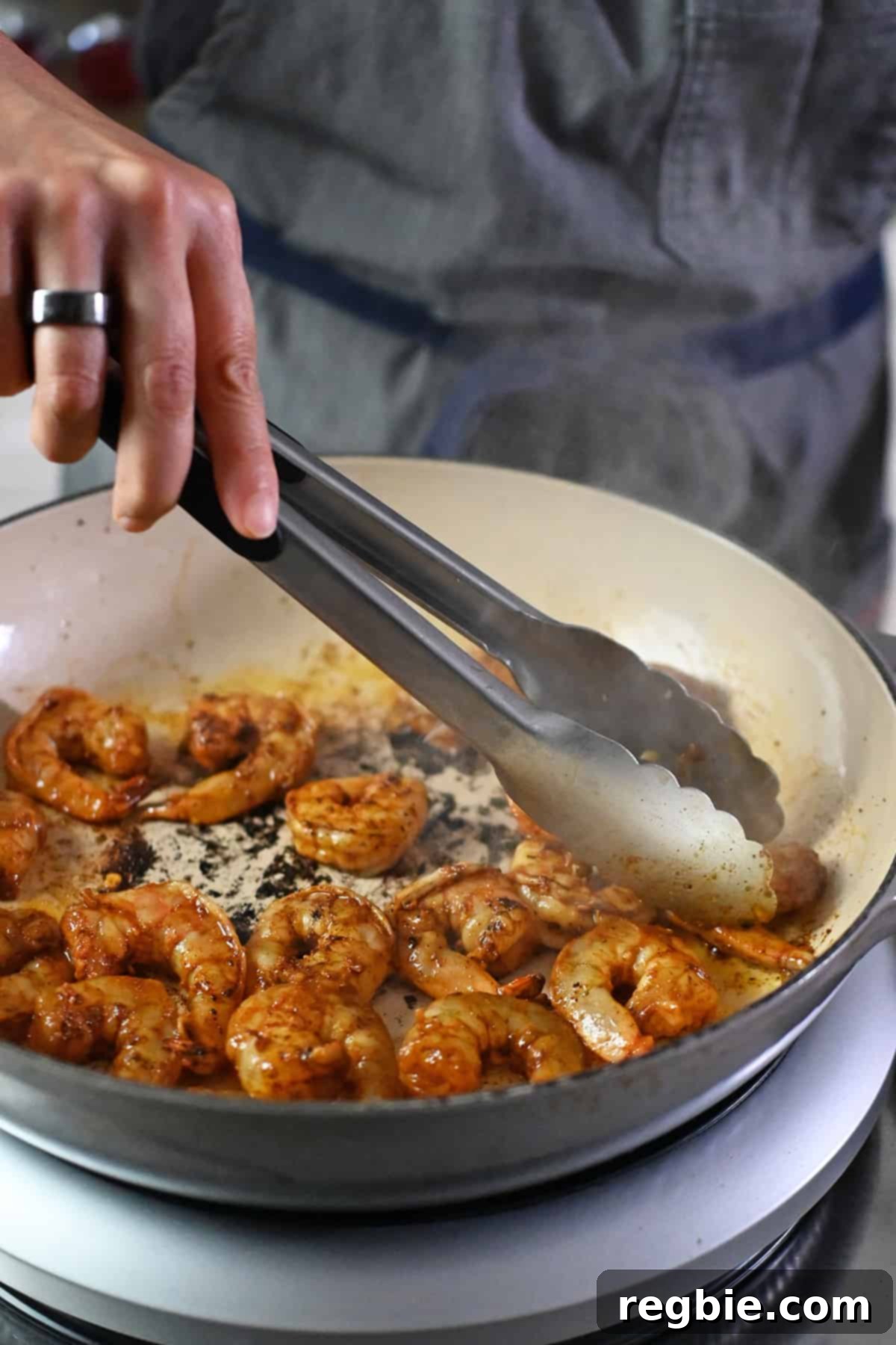 The second half of the seasoned shrimp expertly cooking in the cast iron skillet, achieving a perfect sear for the delicious shrimp fajitas.