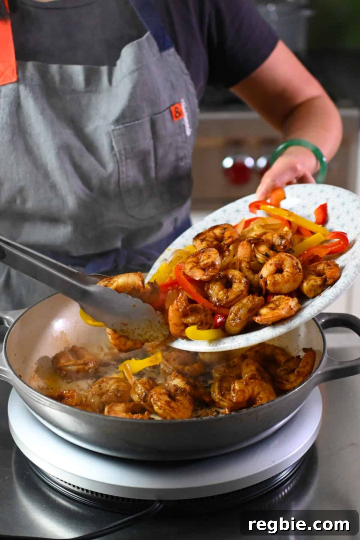 The final step of combining all the cooked fajita vegetables and shrimp back into the skillet, ensuring all the flavors meld together for a harmonious dish.