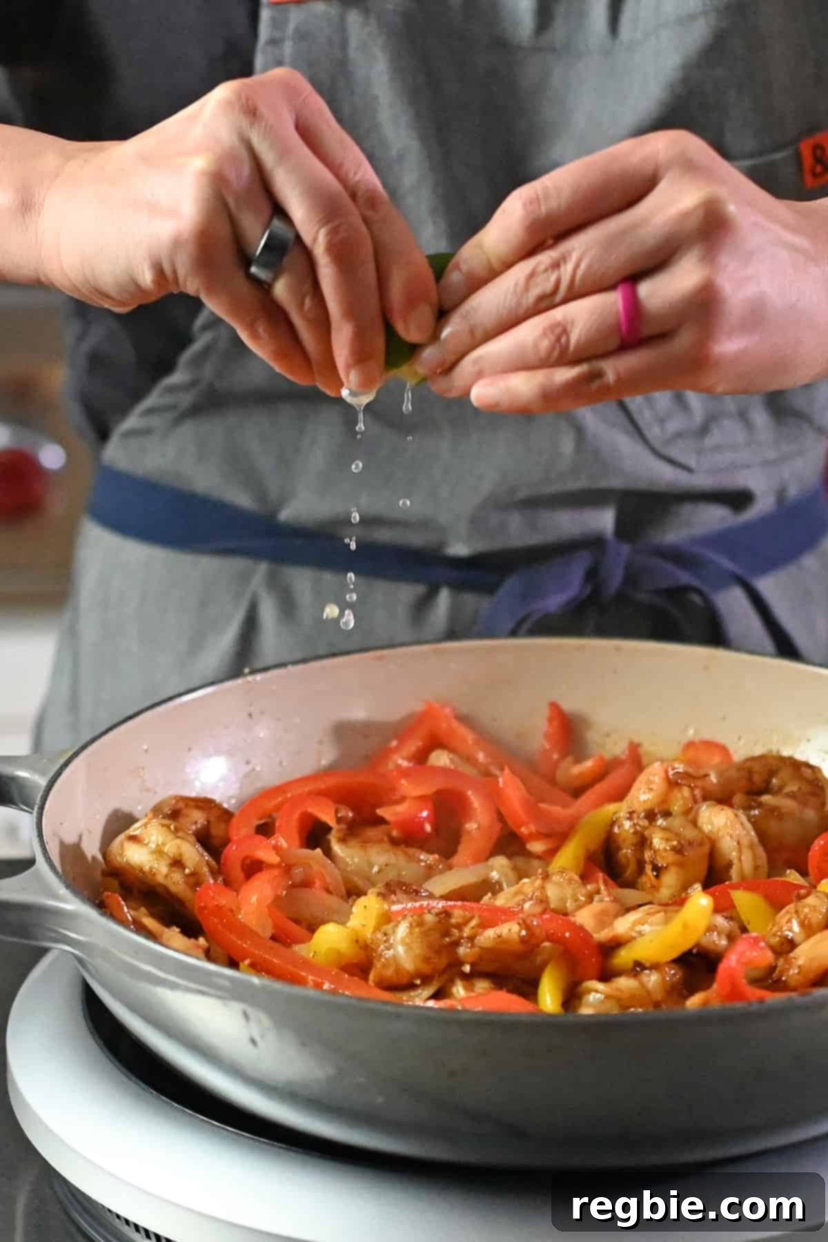 A hand enthusiastically squeezing fresh lime juice over a pan of freshly cooked, sizzling shrimp fajitas, adding a crucial burst of citrusy freshness.