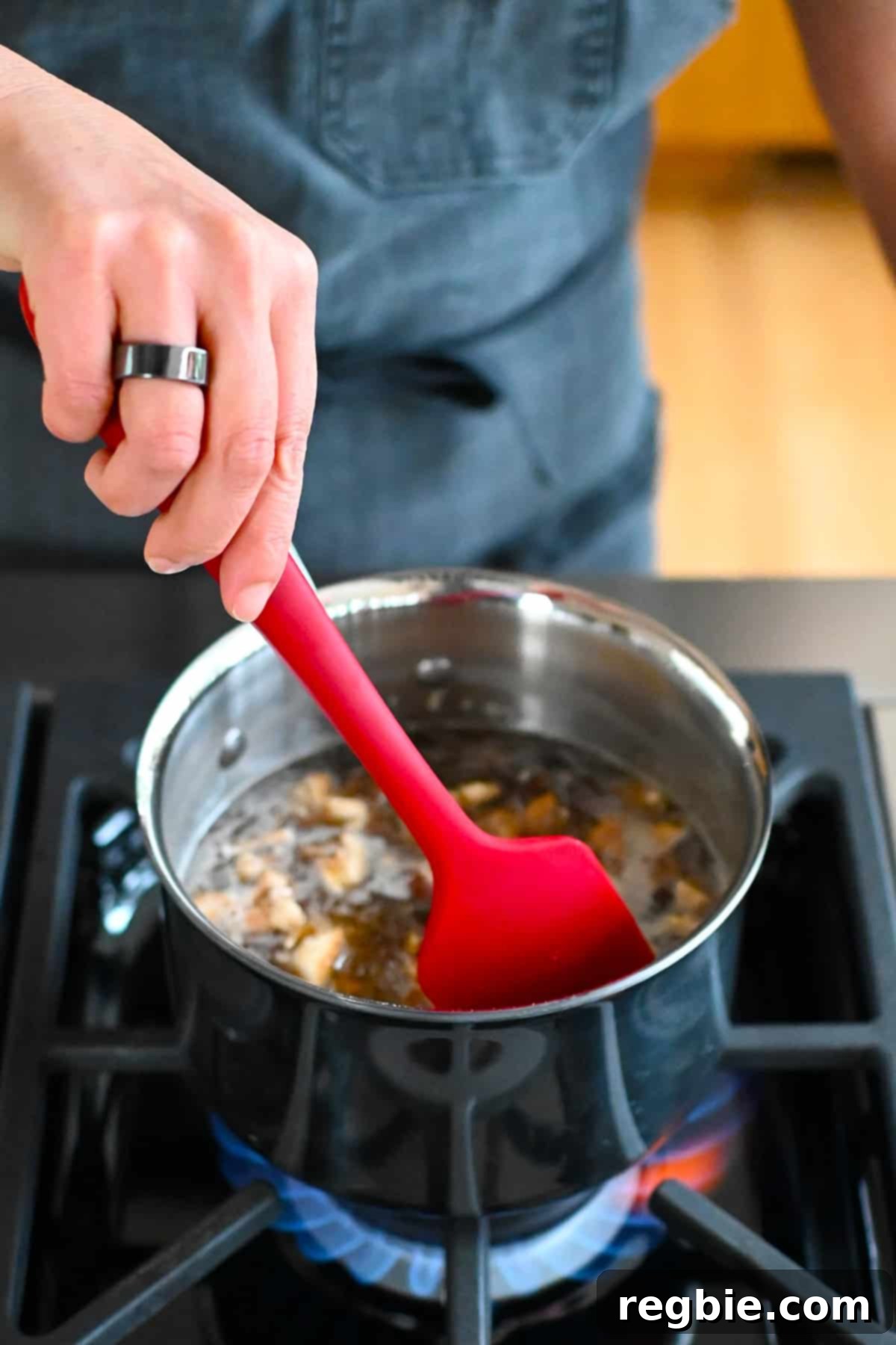 Oceanic Savory Drip 7 A red silicone spatula is used to stir the vegan fish sauce simmering in a small saucepan.