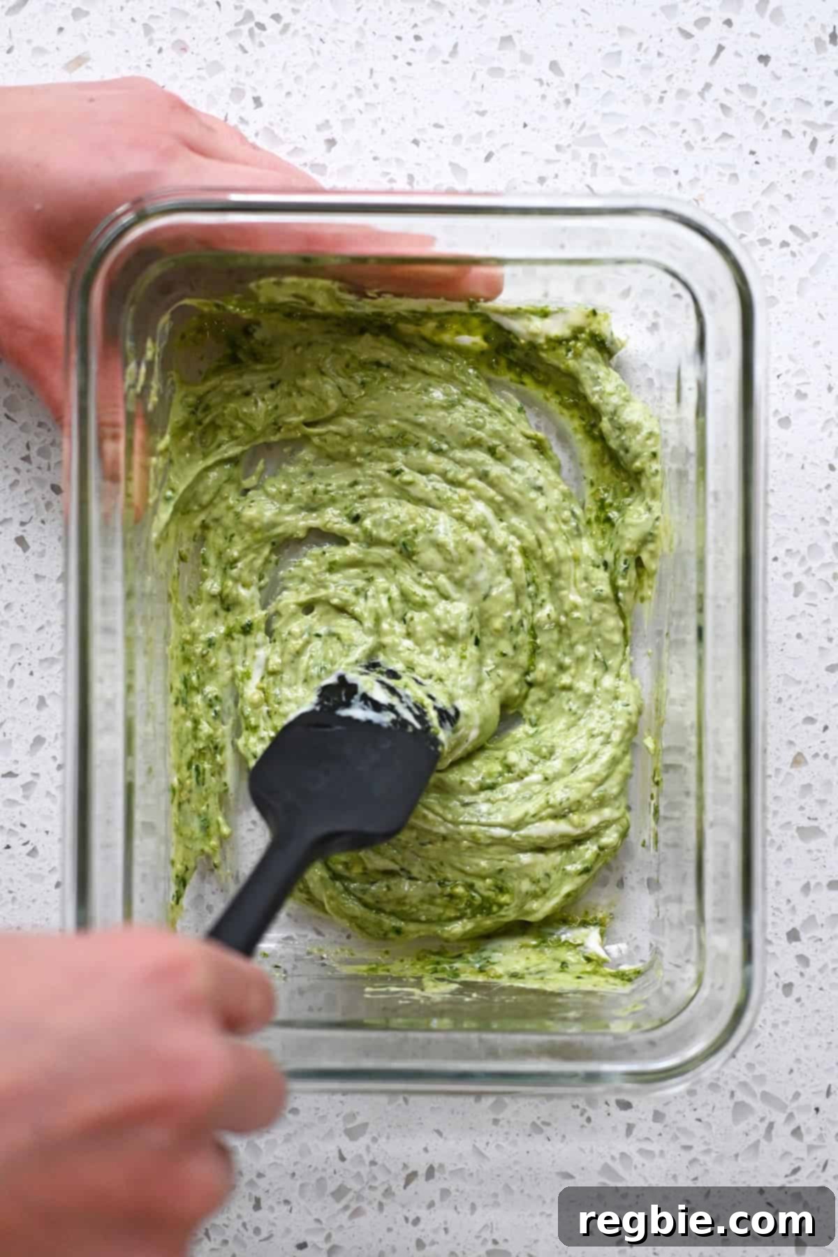 Savory Pesto Chicken 9 An overhead shot of a glass storage container with some mayonnaise mixed with pesto in a one-to-one ratio.