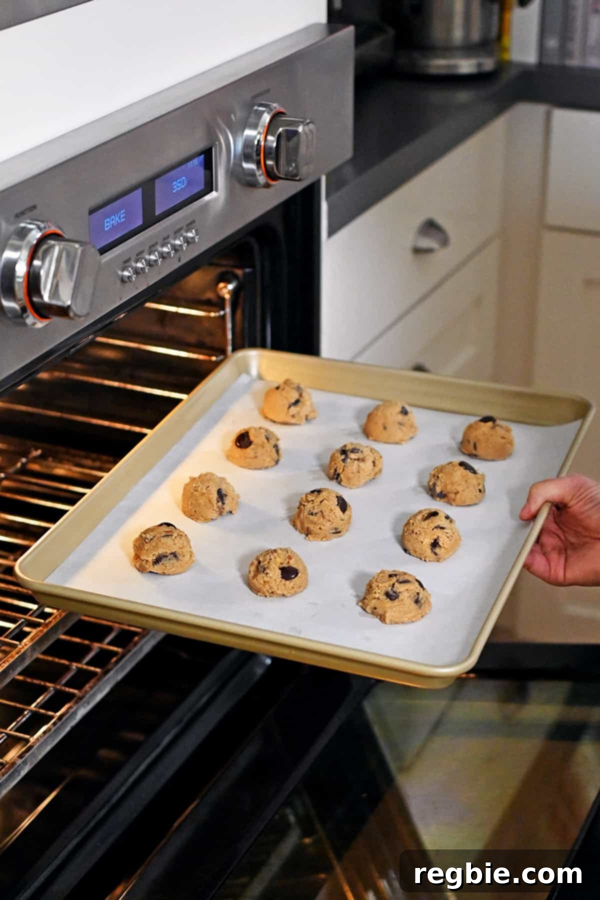 Placing a rimmed baking pan filled with banana cookie dough balls into an open oven to bake, illustrating the start of the baking process.