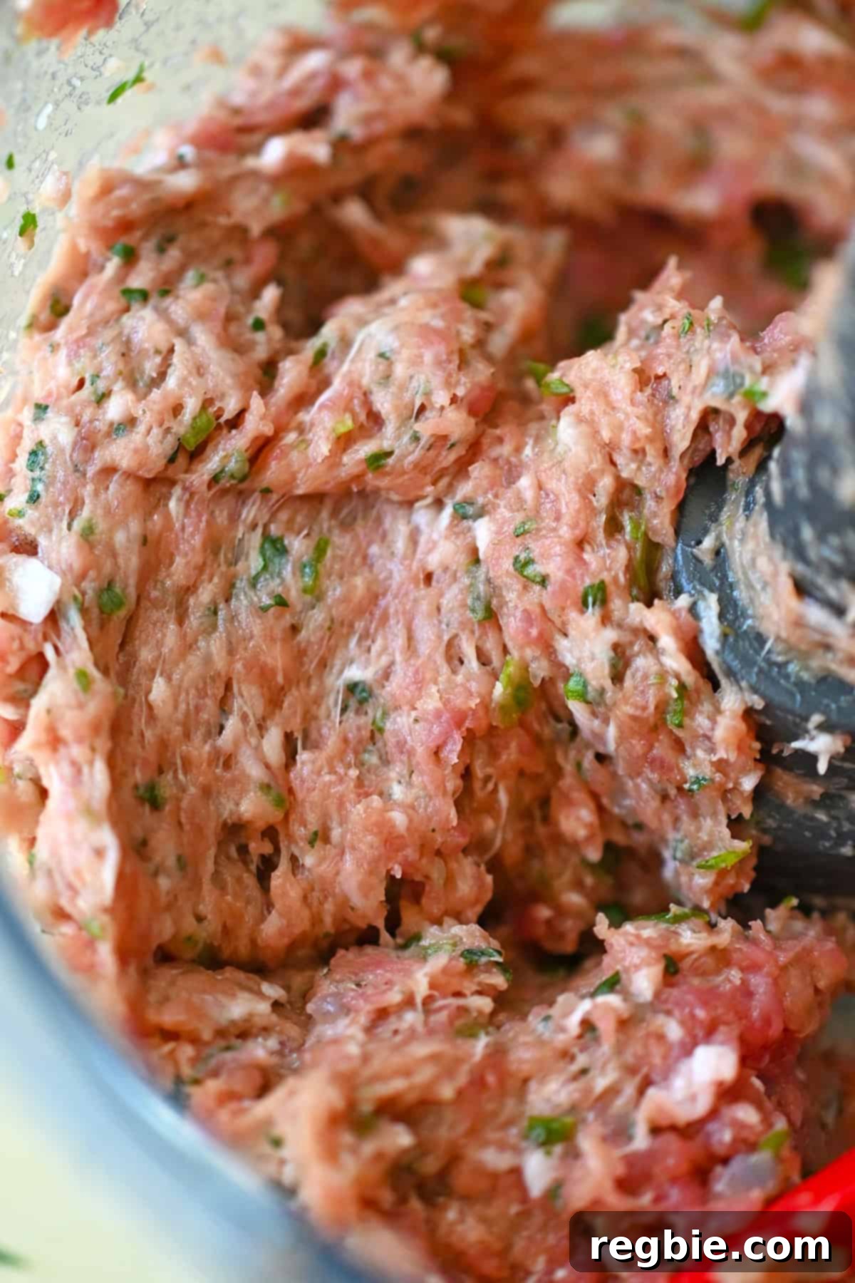 A detailed close-up shot of the finely chopped and mixed dumpling filling inside an open food processor, showcasing its sticky and tacky texture.