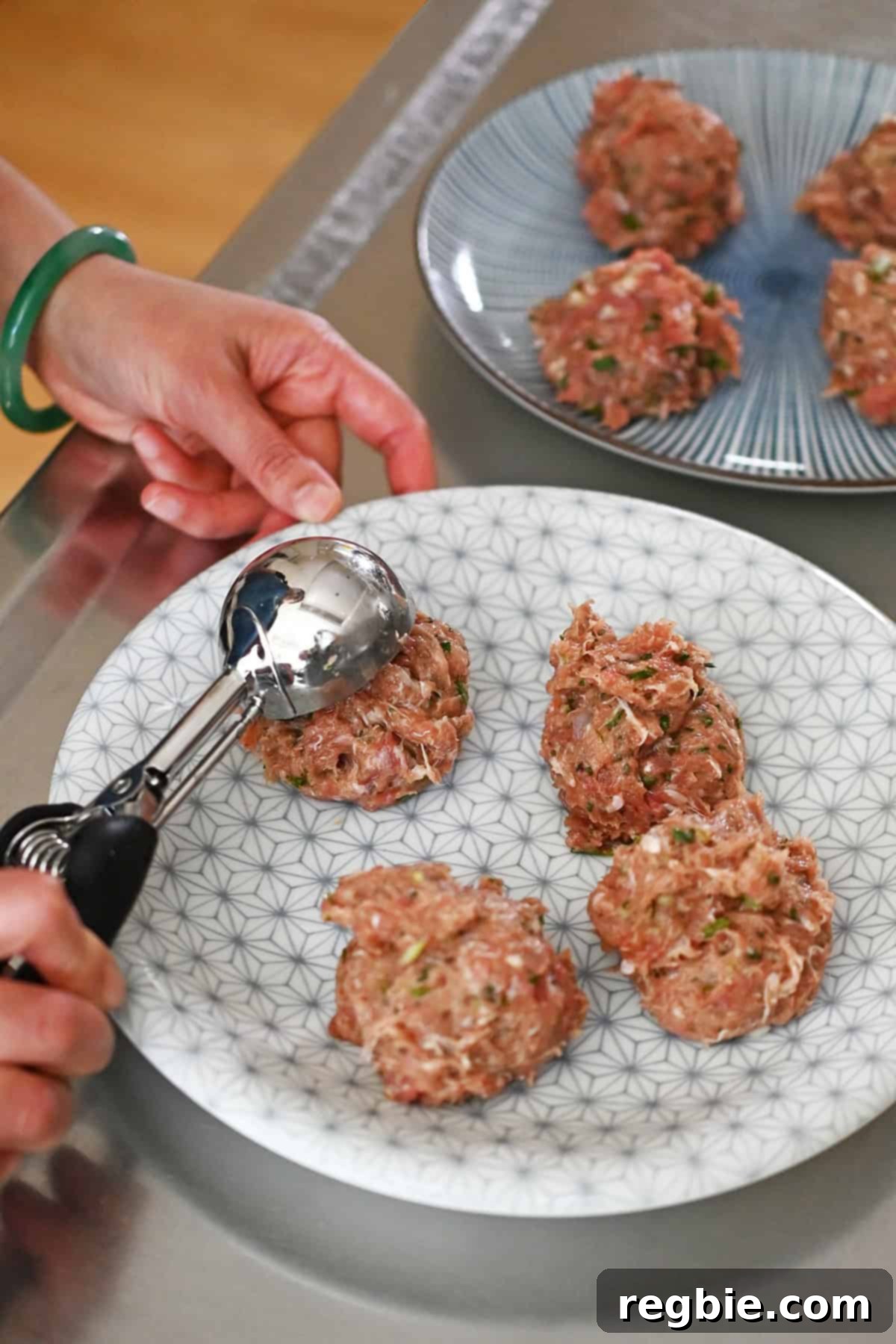 An ice cream scooper is used to portion out the raw dumpling filling into eight uniform balls, ready for the next step of making smash tacos.