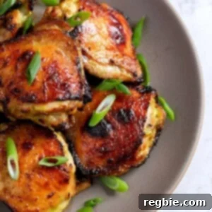 An overhead shot of a platter of Asian Chicken Thighs topped with sliced scallions.