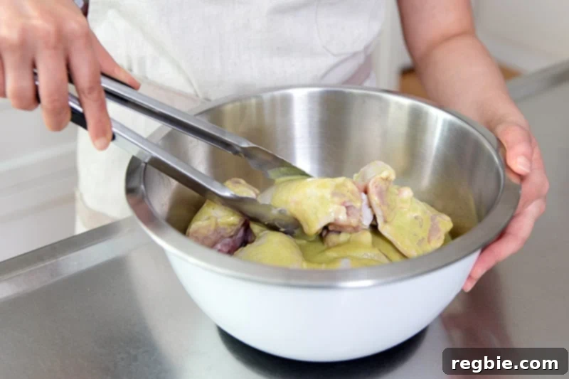 Tossing chicken thighs in a bowl filled with marinade with a pair of tongs.