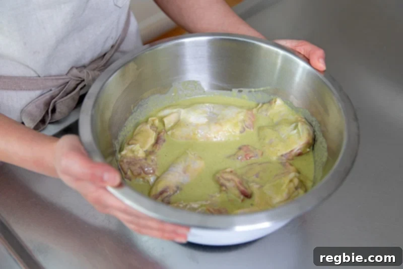 Someone holding a bowl of marinated chicken that have been removed from the fridge.