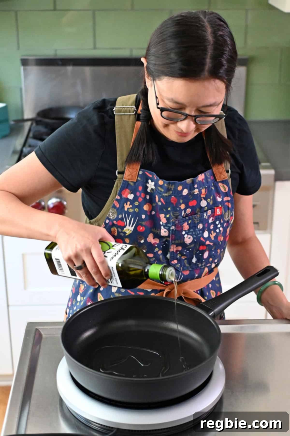 Cantonese Chicken and Mushroom Medley 11 An Asian woman is adding avocado oil to a skillet before making moo goo gai pan.