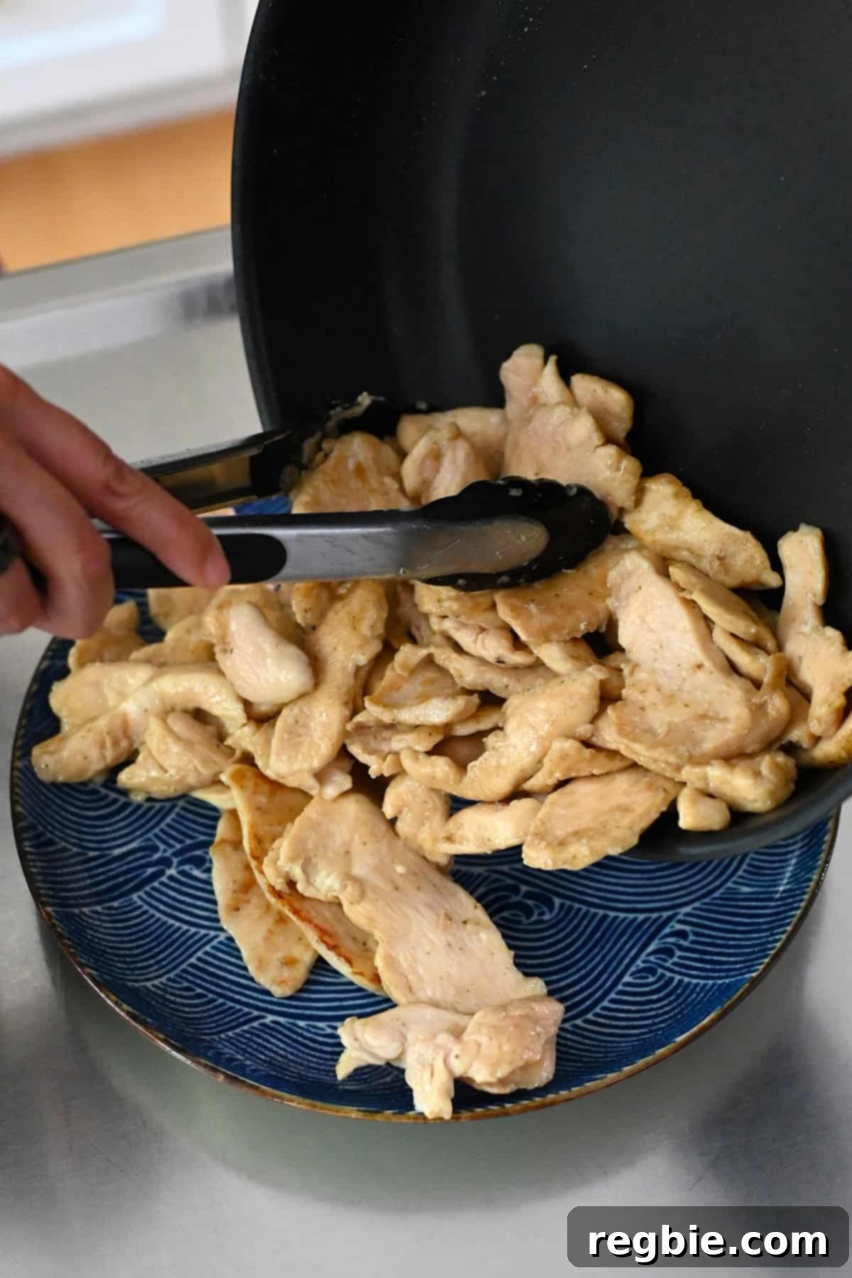 Cantonese Chicken and Mushroom Medley 14 Transferring sautéed chicken breast slices from a frying pan to a plate.