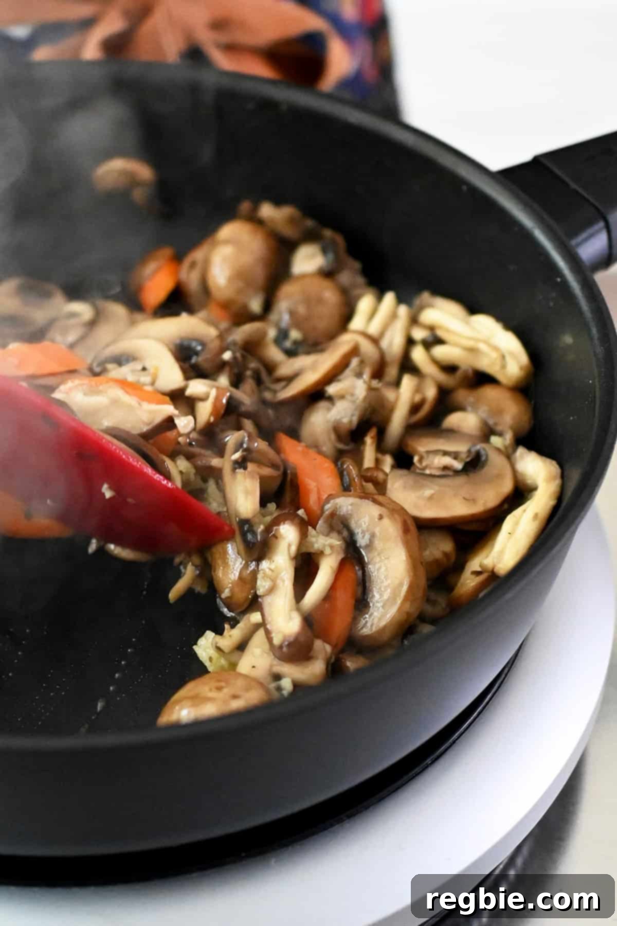 Cantonese Chicken and Mushroom Medley 18 A closeup shot of sautéed sliced mushrooms and sliced carrots with minced garlic and ginger in a frying pan.