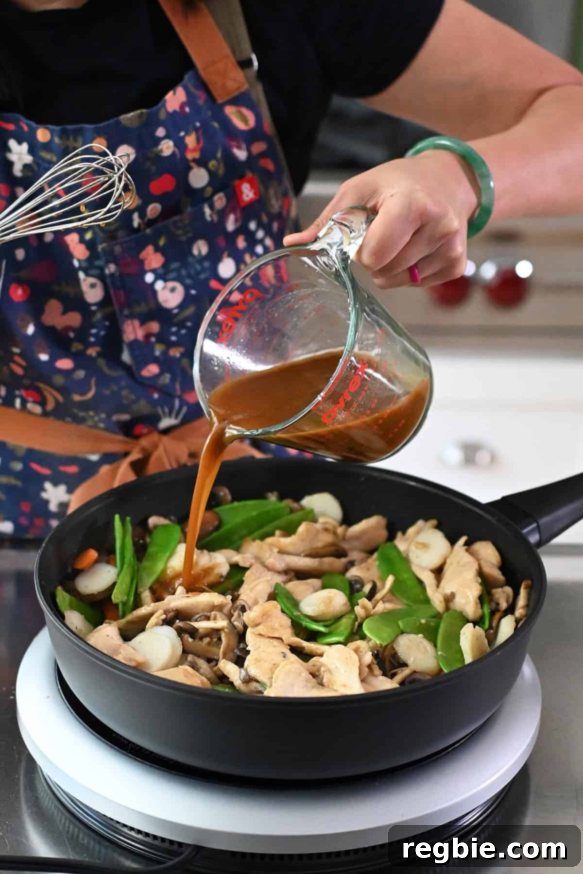 Cantonese Chicken and Mushroom Medley 20 Pouring the brown sauce into a frying pan with sautéed mushrooms, veggies, and chicken to make moo goo gai pan.