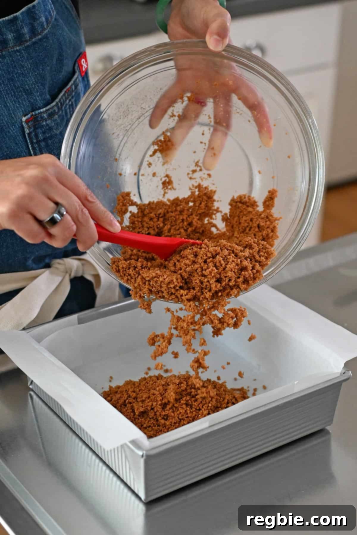 Golden Harvest Pumpkin Bars 12 Adding the cookie crumb crust to the parchment paper lined square baking pan.