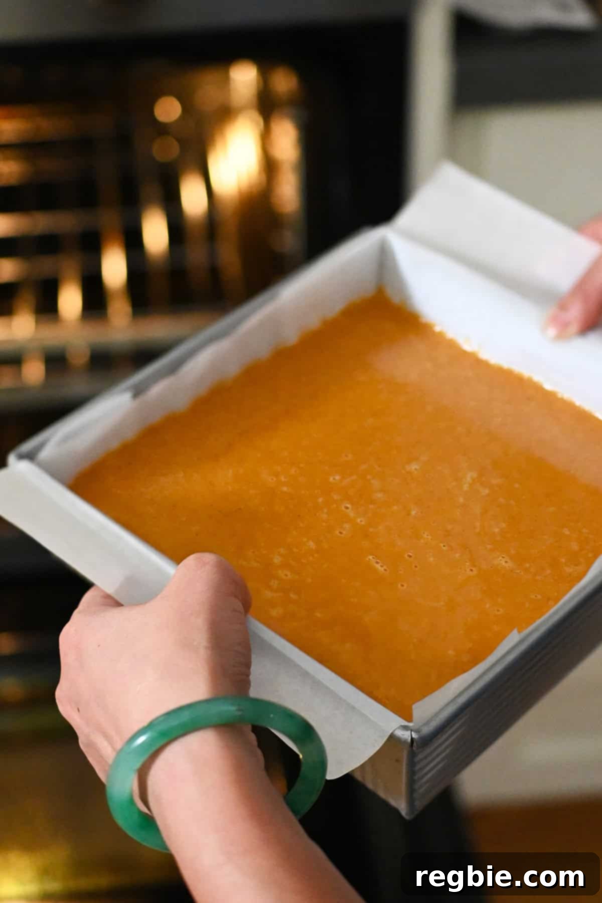 Golden Harvest Pumpkin Bars 21 Placing the pumpkin pie bars square pan into the oven to bake.