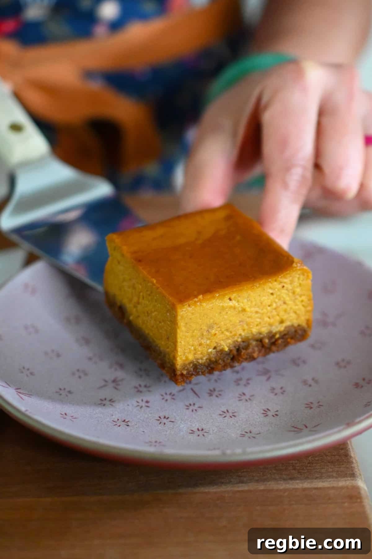 Golden Harvest Pumpkin Bars 24 Placing a square of pumpkin pie bars onto a pink plate.