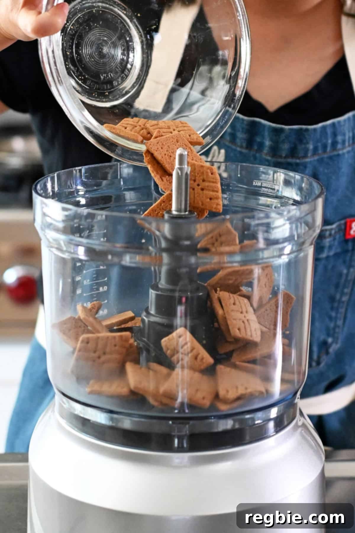Golden Harvest Pumpkin Bars 8 Adding grain-free cookies from a glass bowl into an open food processor bowl.