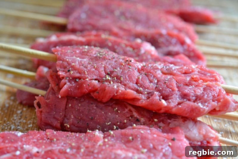 Flattened steak skewers are seasoned with salt and pepper .