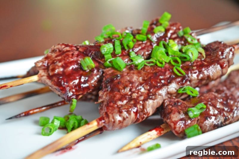 A dish filled with Smashed Steak Skewers topped with Whole30 cherry BBQ sauce and sliced scallions.