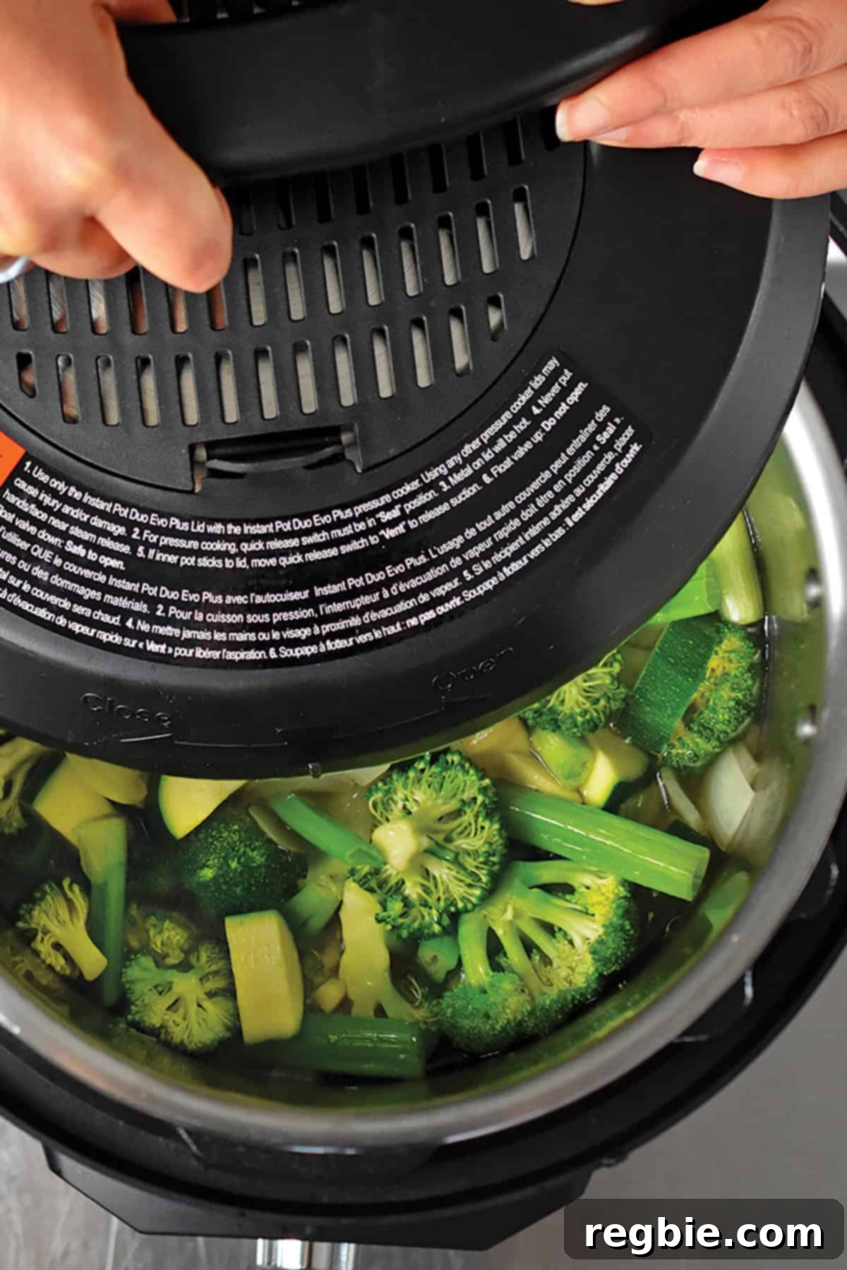 An overhead shot showing the lid being placed and secured onto the Instant Pot, sealing in the ingredients for the green soup.