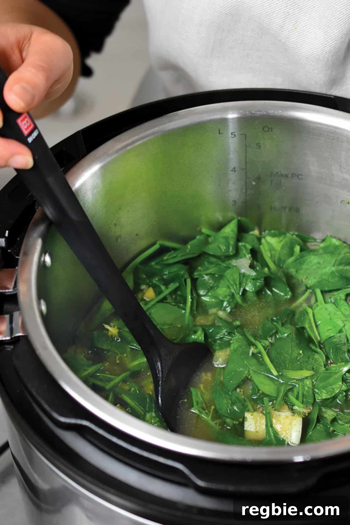 An overhead shot of the Instant Pot containing all the cooked ingredients for the green soup, including wilted spinach, ready for blending.