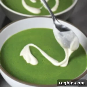 A bowl of vibrant green soup topped with a dollop of creamy cashew sauce.
