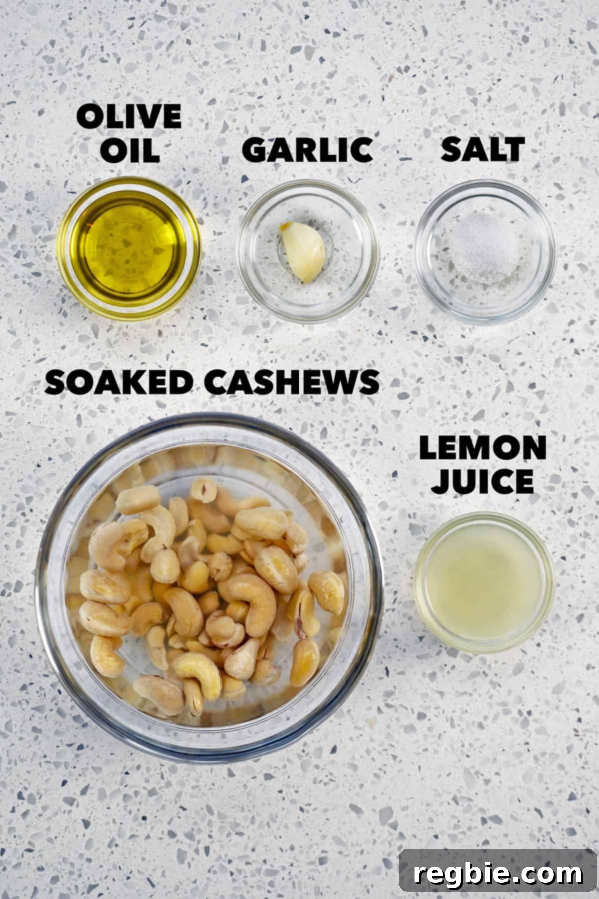 An overhead shot showcasing the fresh ingredients laid out for making the dairy-free cashew cream, including raw cashews, lemon, and garlic.