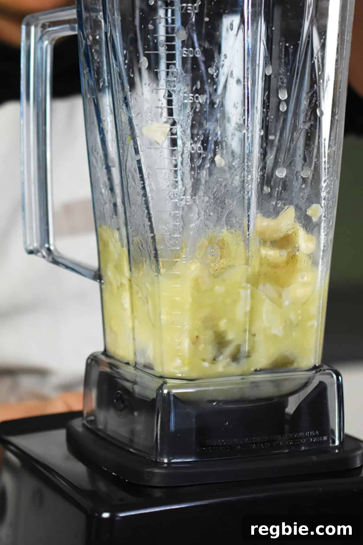 A high-speed Vitamix blender actively blending the cashews and other ingredients into a smooth, thick, dairy-free cashew cream.