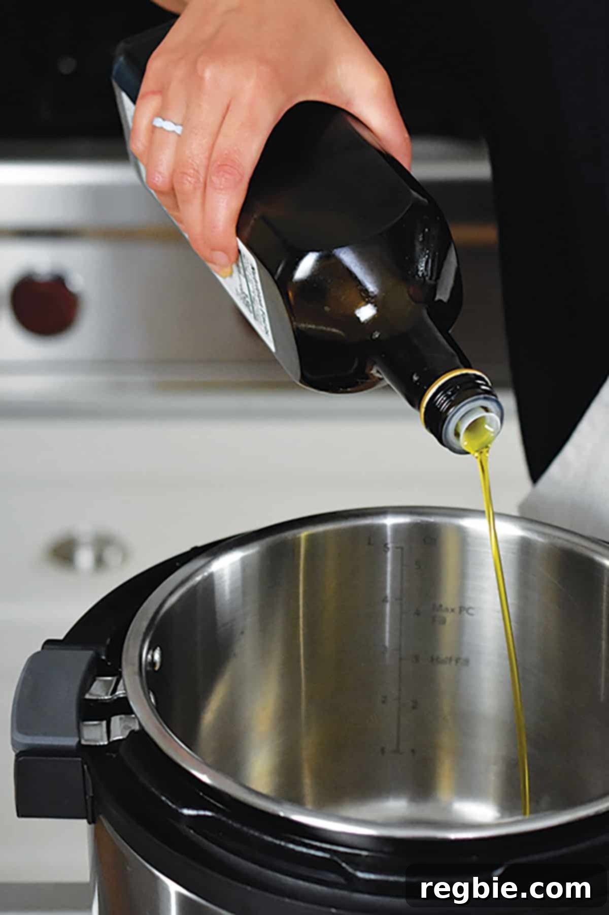 A stream of extra virgin olive oil being poured into the hot inner pot of an Instant Pot, preparing for sautéing.