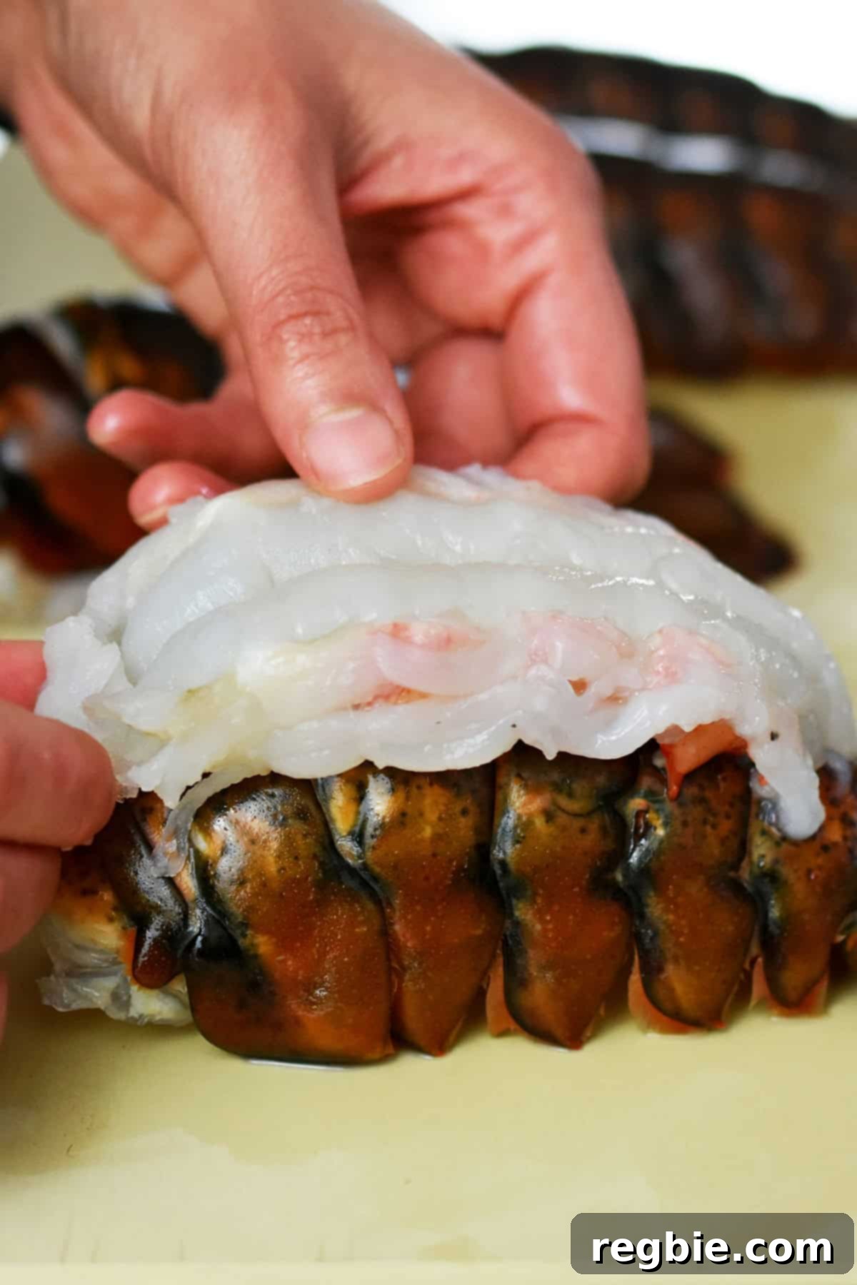 Laying the butterflied raw lobster tail meat on top of the shell before baking it in the oven.