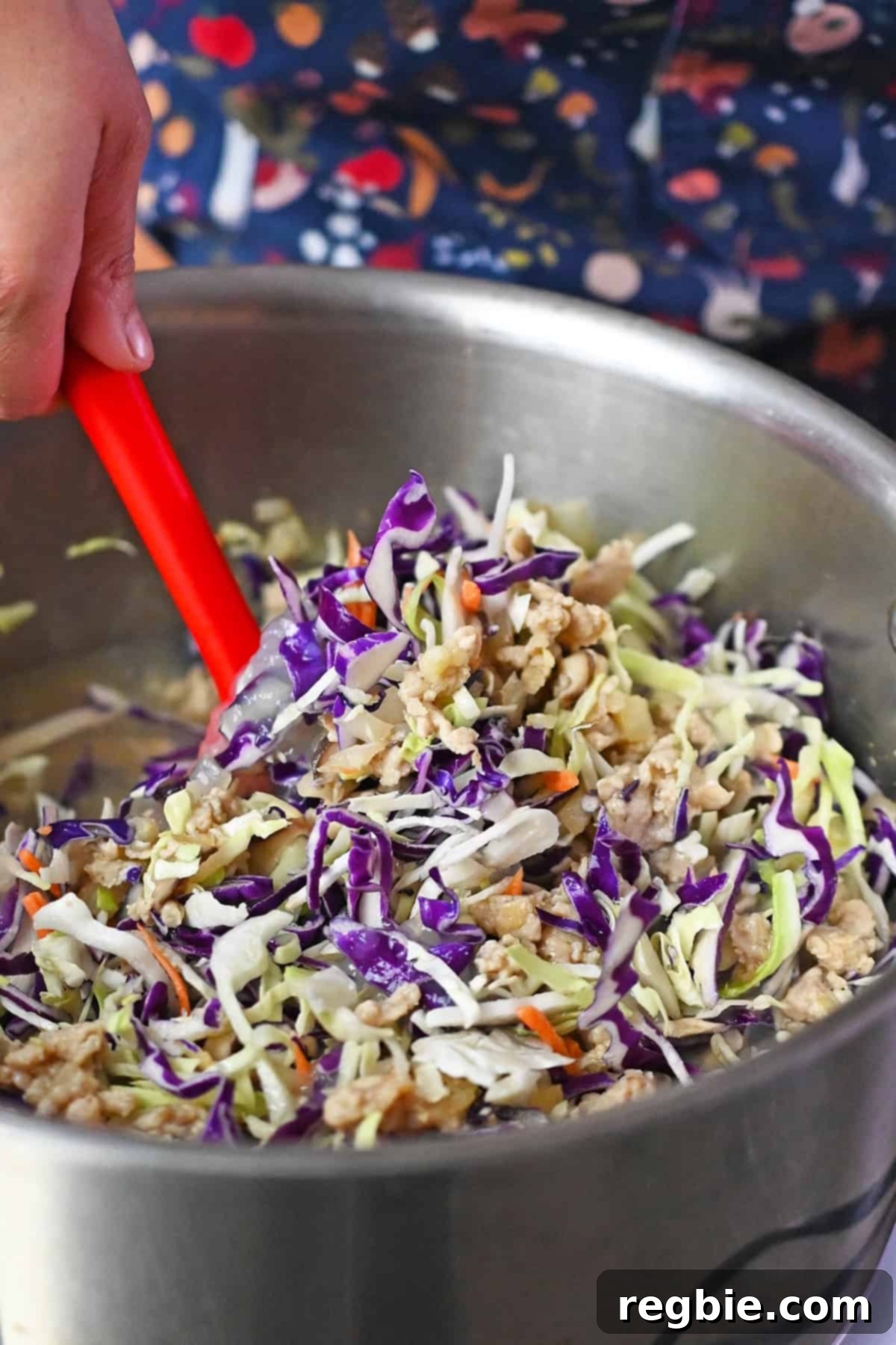 A closeup of someone stirring the ingredients for cabbage and chicken soup in a large stock pot.