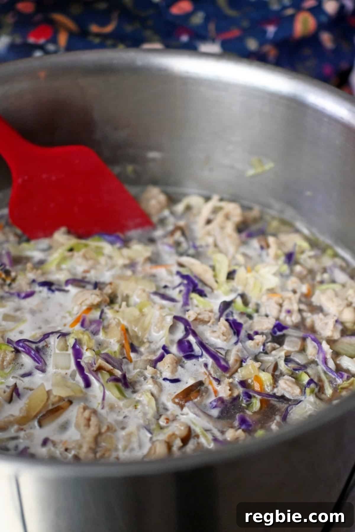 A closeup of simmering Asian chicken and cabbage soup in a large pot.