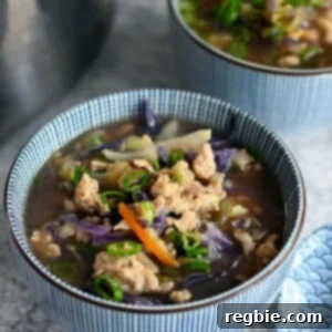 A closeup of a blue and white bowl filled with Asian cabbage and chicken soup.
