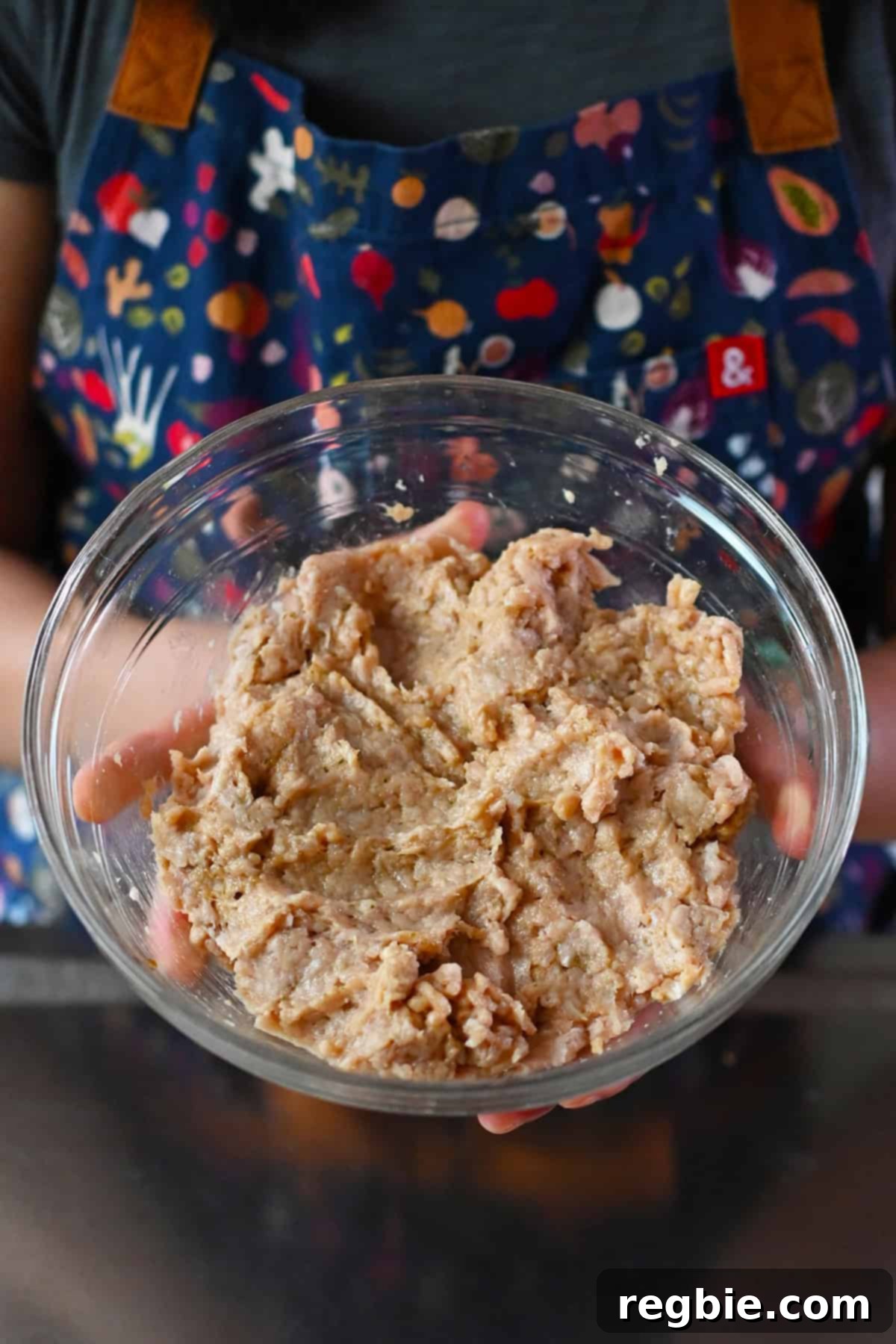 A closeup view of a bowl of seasoned raw ground chicken marinating for Asian chicken and cabbage soup.