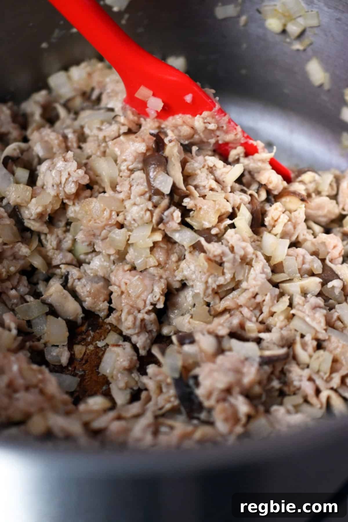 A close-up of the cooked ground chicken, shiitake mushrooms, and onions in a large stockpot.