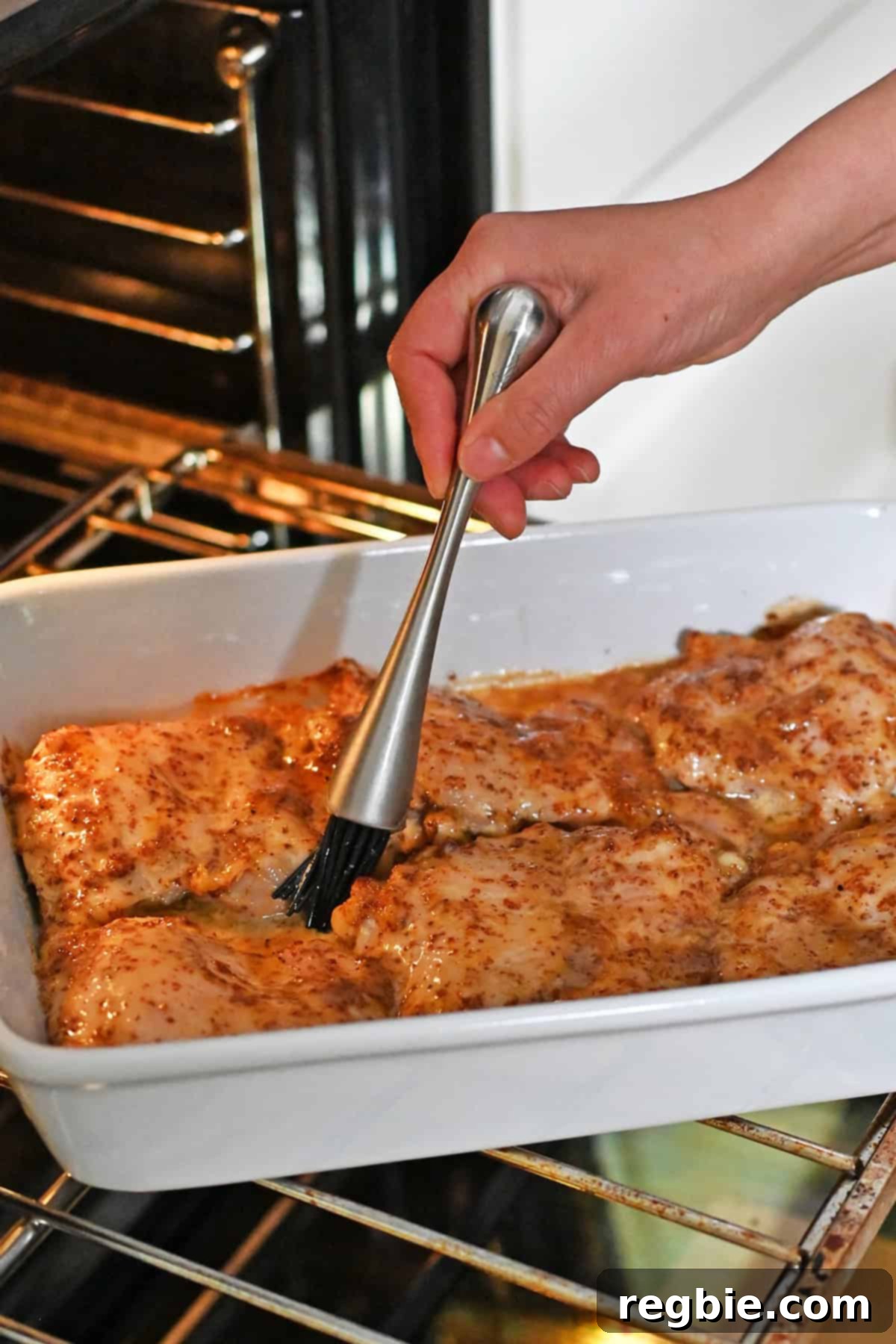 Brushing honey mustard sauce on the chicken thighs after the dish has baked for 15 minutes.