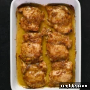 An overhead shot of someone holding a rectangular white baking dish filled with baked honey mustard chicken thighs.