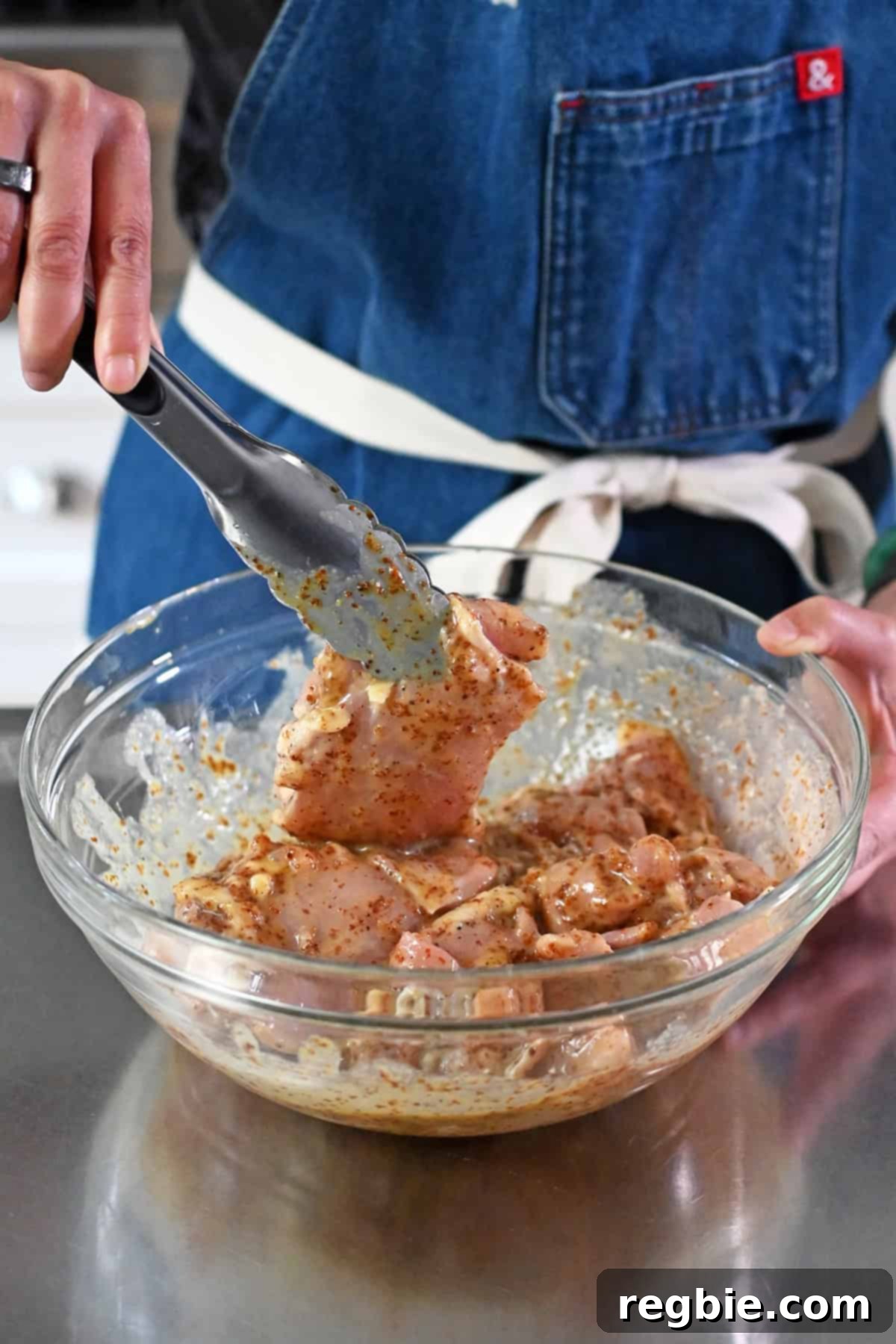 Tossing the raw chicken thighs in the honey mustard marinade so the thighs are well coated with the sauce.