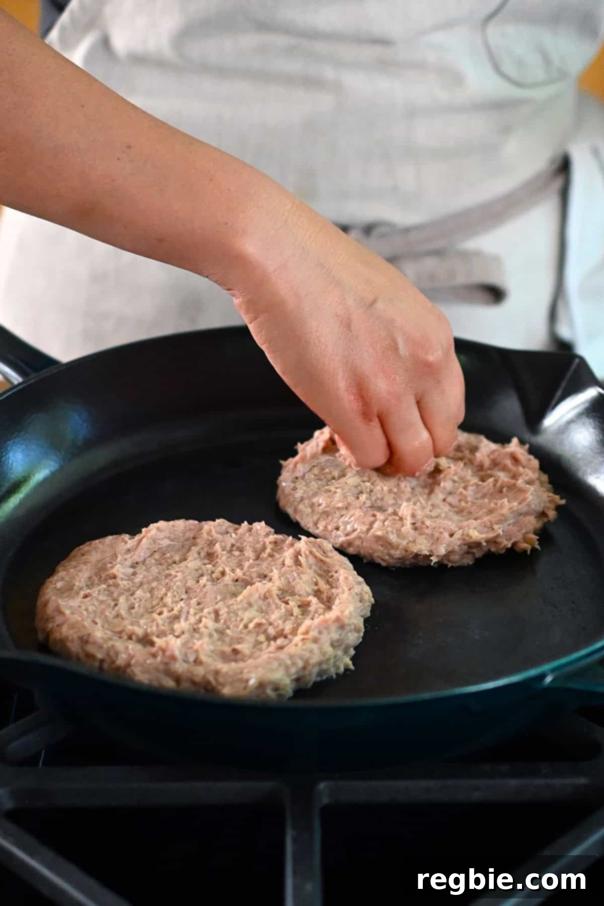Pressing the turkey burgers into a skillet and making sure they are half-inch thick.