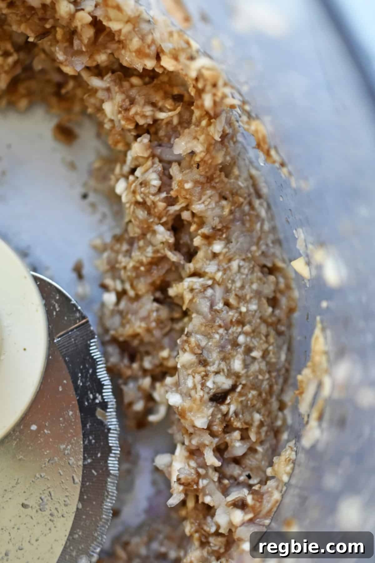 An overhead shot of finely chopped mushrooms and shallots in an open food processor, part of the turkey burger filling.