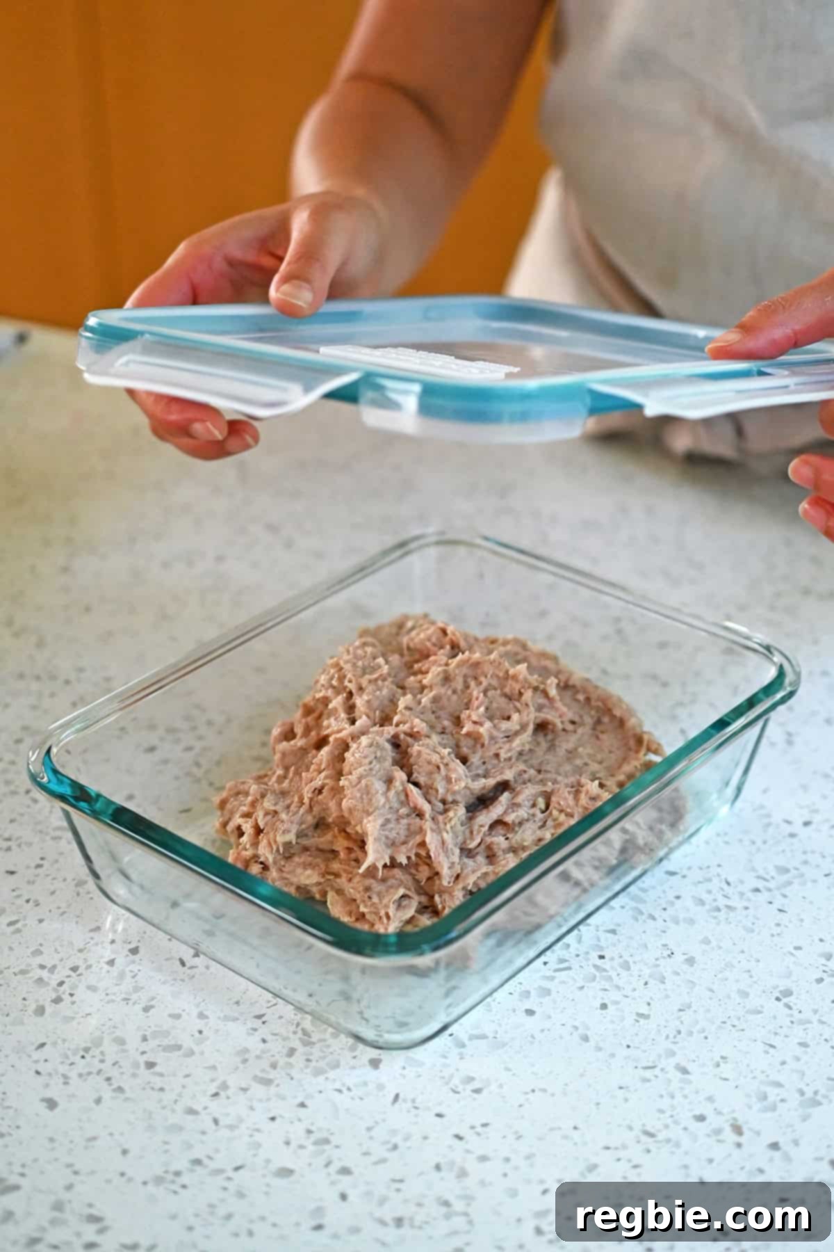 Raw turkey burger mixture is being placed into a covered air tight container before being chilled in the fridge.