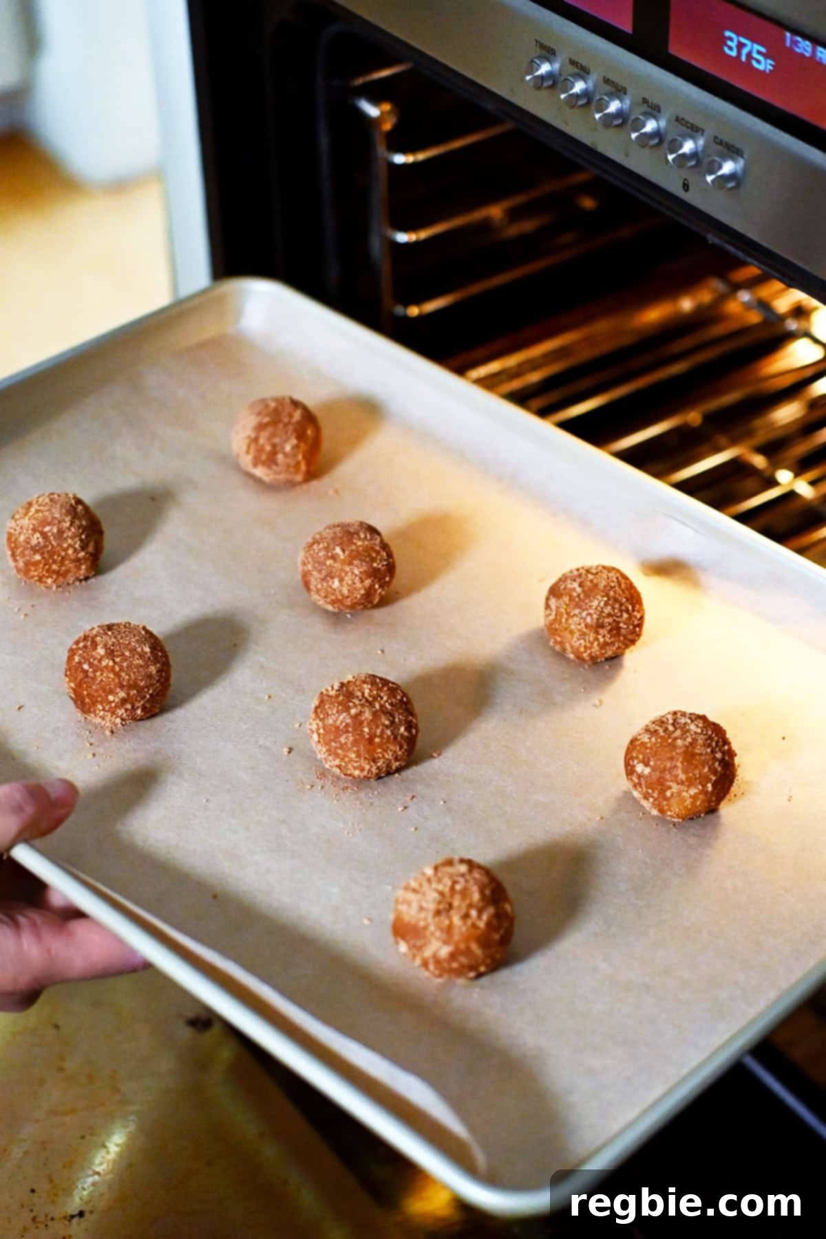 Placing a baking sheet with pumpkin snickerdoodle cookie dough balls into a hot oven.