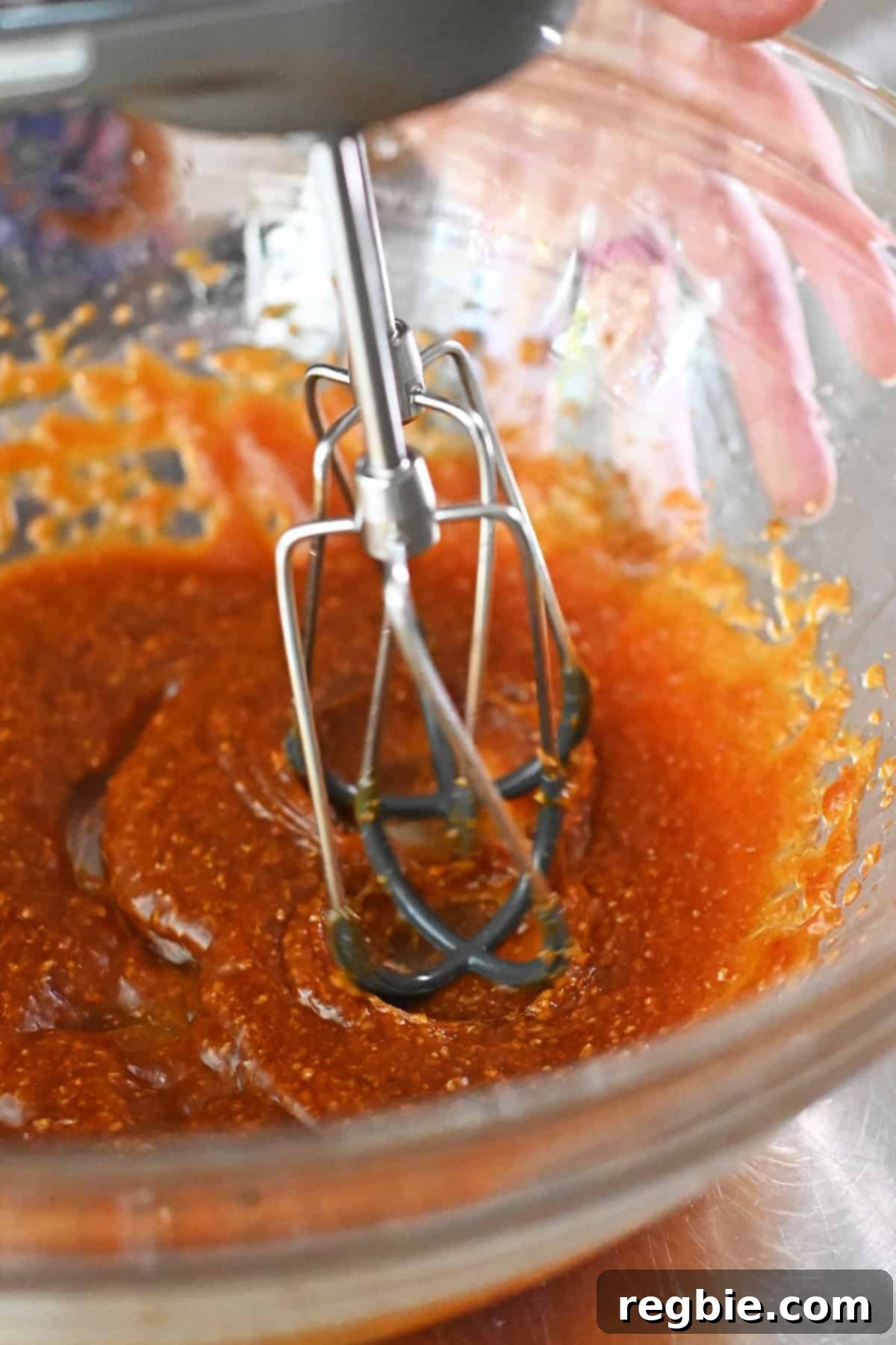 Using a hand mixer to combine the coconut sugar, melted coconut oil, pumpkin puree, and vanilla extract.