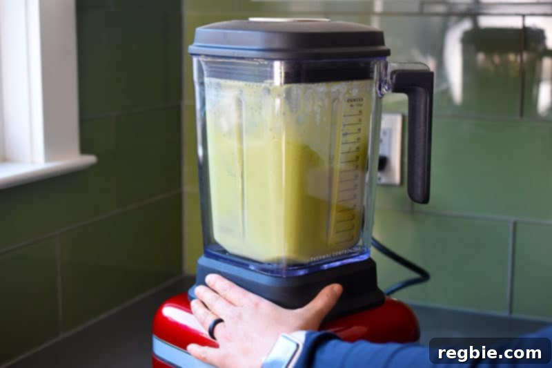The matcha, coconut cream, and coconut water mixture being blended in a high-speed blender, creating a smooth green liquid.