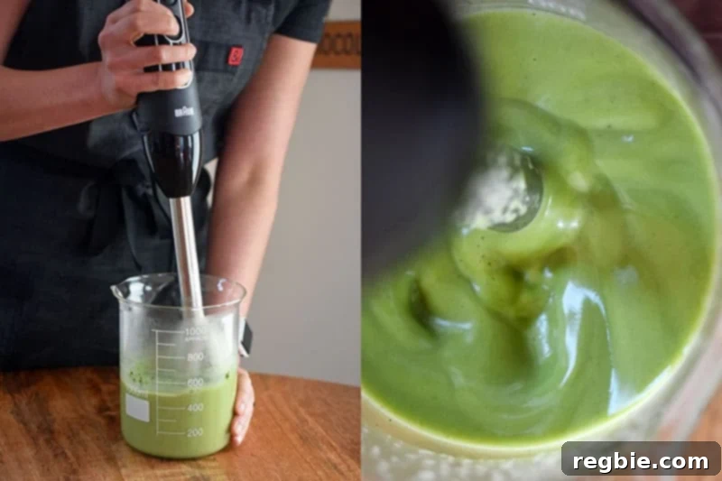 An immersion blender being used to mix the matcha coconut gummy ingredients directly in a glass beaker.