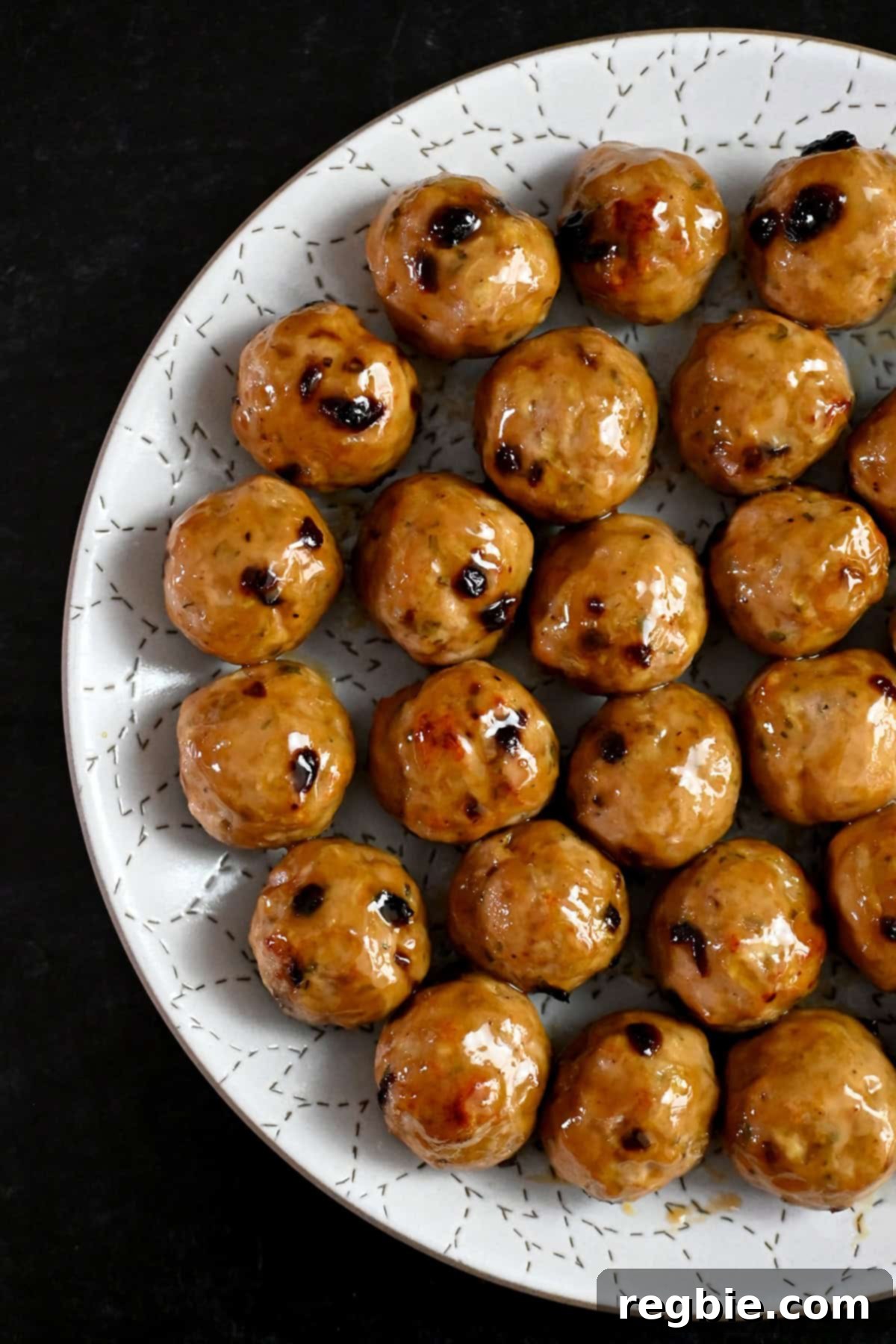 An overhead shot of a white plate topped with cranberry turkey meatballs topped with a gluten free maple Dijon mustard glaze.