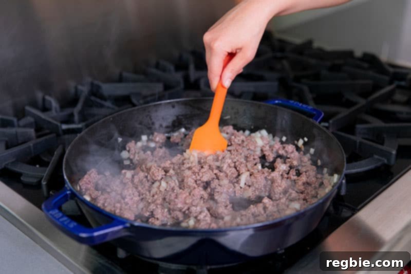 One Pan Beef Cabbage Wonder 9 A cast iron skillet holds a perfectly cooked mixture of ground beef and diced onions, showcasing a rich, browned texture ready for the next step.