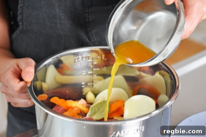 A steady stream of fresh orange juice being poured into the Instant Pot, mixing with the seasoned pork and other ingredients for the carnitas.