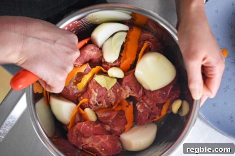An overhead shot showing someone gently mixing the pork and other carnitas ingredients inside the Instant Pot insert, ensuring everything is well combined.