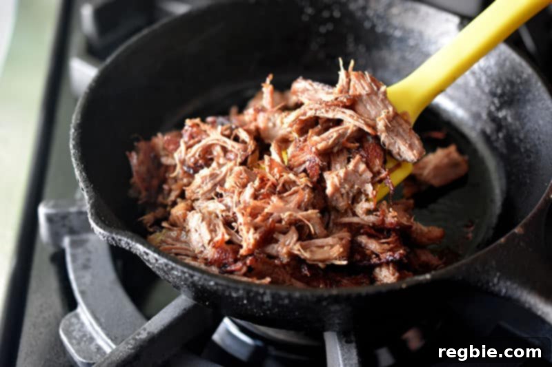 Crispy Instant Pot Carnitas sizzling and browning in a hot cast iron skillet, achieving a perfect golden texture.