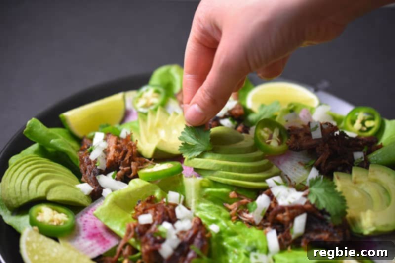 A beautifully arranged platter showcasing Instant Pot Carnitas, accompanied by fresh cilantro, crisp lettuce leaves, creamy sliced avocados, vibrant jalapeños, zesty lime wedges, and thinly sliced radishes, ready for assembly.