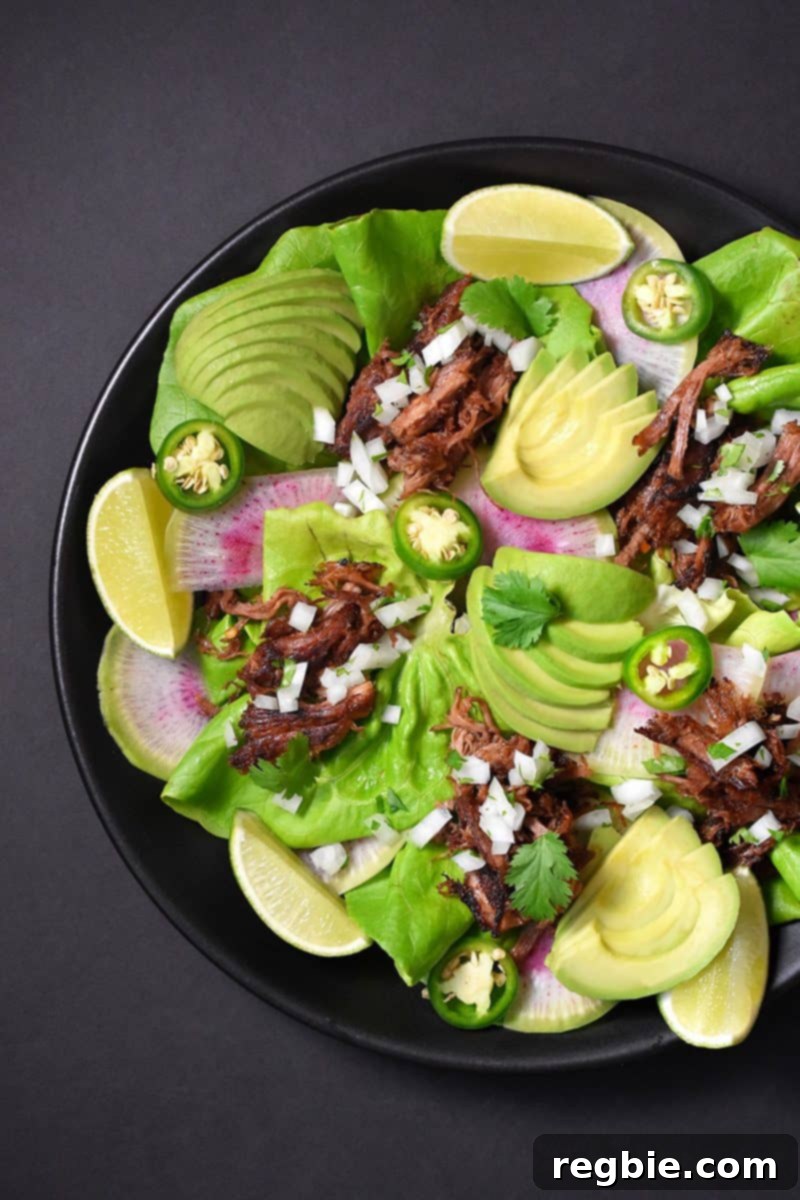 A delectable bowl of Instant Pot carnitas, beautifully presented with vibrant garnishes including fresh lettuce, zesty limes, creamy avocados, and spicy jalapenos, inviting you to create your perfect meal.